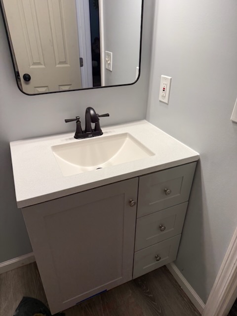New bathroom vanity with solid surface top, black faucet and framed mirror